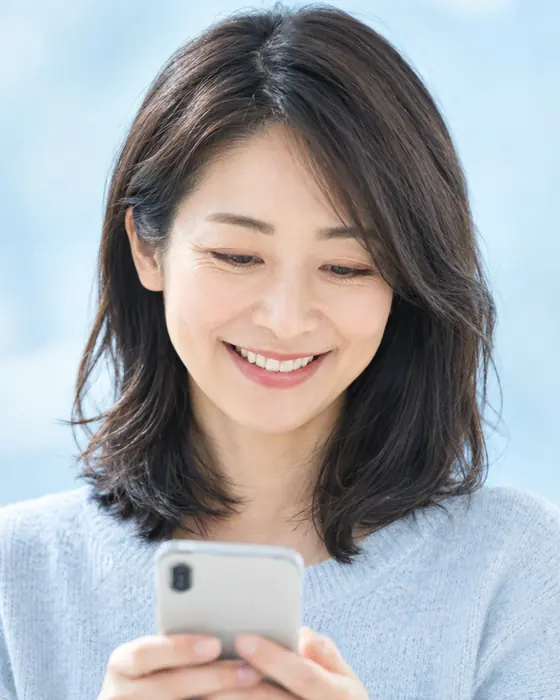 A woman smiling at her smartphone
